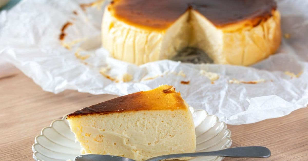 Tarta de queso dorada y cremosa, recién salida de la freidora de aire, presentada en un plato rústico español con un toque de frutos rojos.